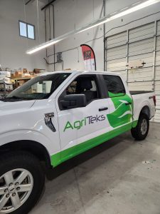 AgriTeks pickup truck with green partial wrap and commercial business graphics