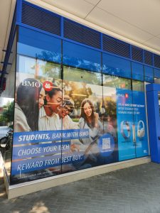 Large-format BMO promotional window graphics installed across a commercial storefront